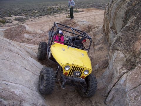 1989 Ford Bronco - Off-road buggy tackling a steep, rocky incline with two occupants.
