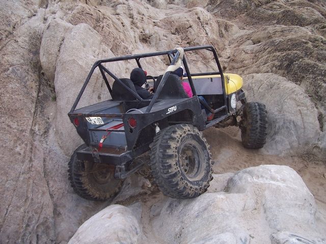 Buggy climbing rocks, driver and passenger visible. Roll cage and large tires