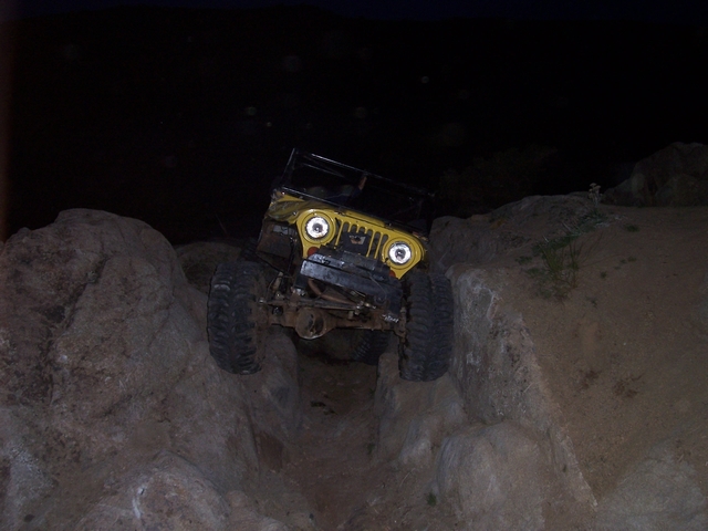 Yellow off-road vehicle climbing rocks at night