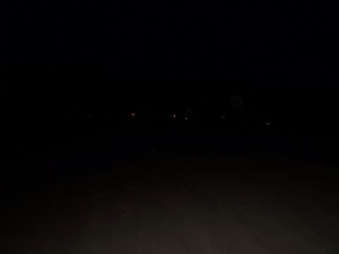 1989 Ford Bronco - Distant lights are visible in the dark night sky, possibly from a town or other structures.
