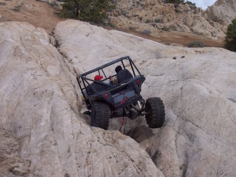 1989 Ford Bronco - This custom buggy is navigating a steep, rocky trail. The vehicle's suspension is clearly being tested.
