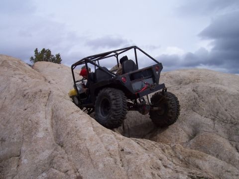 1989 Ford Bronco - An off-road vehicle navigates a challenging rocky terrain under a cloudy sky.