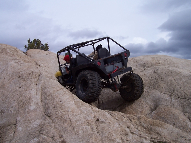 Black off-road vehicle with a roll cage climbing a rocky incline