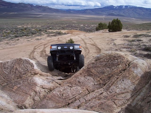 1989 Ford Bronco climbing over rocks in a desert landscape