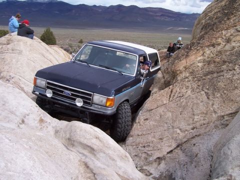 1989 Ford Bronco - This Ford Bronco is navigating a challenging rocky terrain, with people watching from the rocks above.