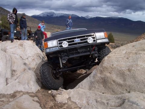 1989 Ford Bronco - A black Ford Bronco navigates a rocky trail with spectators watching.