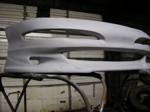 1994 Ford Probe - A custom car bumper, likely for aftermarket modification, is displayed on a stand in a workshop setting.