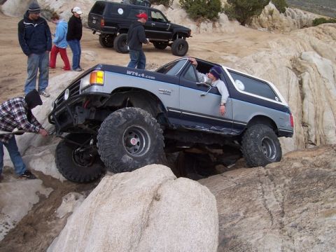 1989 Ford Bronco - A modified Ford Bronco tackles a challenging rock crawl with assistance from a bystander.