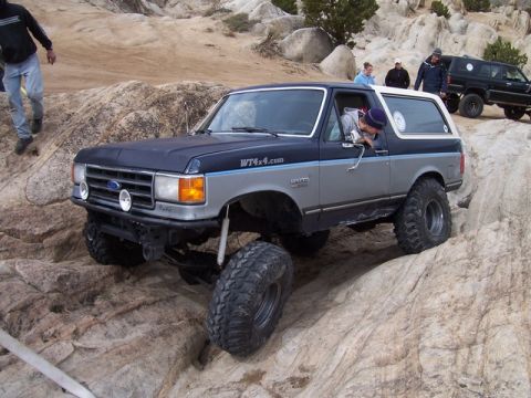 1989 Ford Bronco - This 1989 Ford Bronco is navigating a rocky off-road trail, with another vehicle visible in the background.