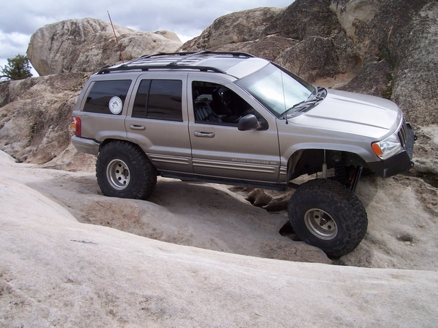 Modified Jeep Grand Cherokee with large tires climbing rocks