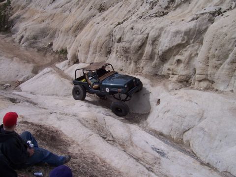 1989 Ford Bronco - A dark green Jeep Wrangler tackles a challenging rocky terrain during an off-road excursion.