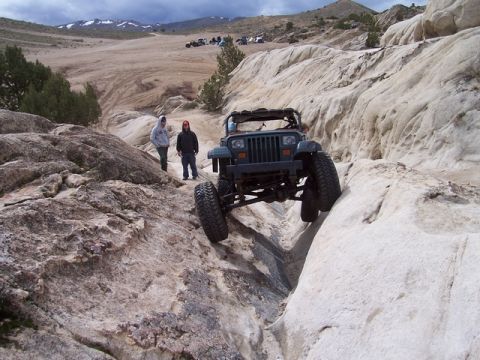 1989 Ford Bronco - A modified Jeep Wrangler TJ navigates a narrow, rocky canyon during an off-road excursion.