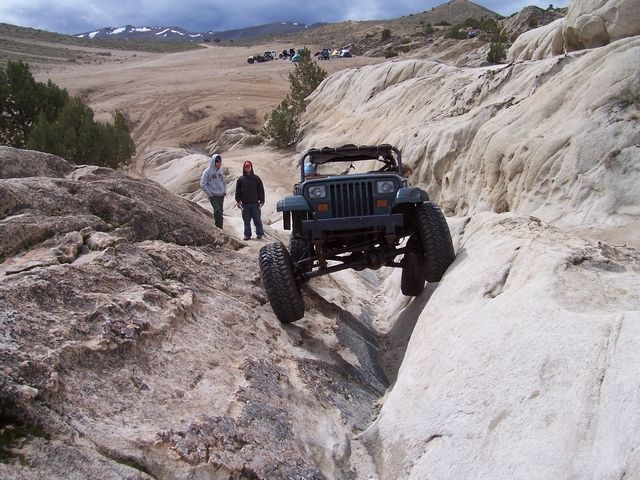 Green Jeep Wrangler TJ off-roading on a rocky trail, front view