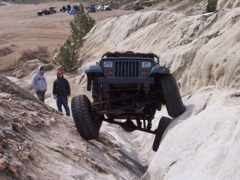 1989 Ford Bronco - A Jeep Wrangler TJ navigates a rocky obstacle during an off-road excursion.