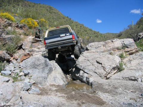1994 Ford Bronco - A 1994 Ford Bronco tackles a challenging rocky terrain in a desert landscape.