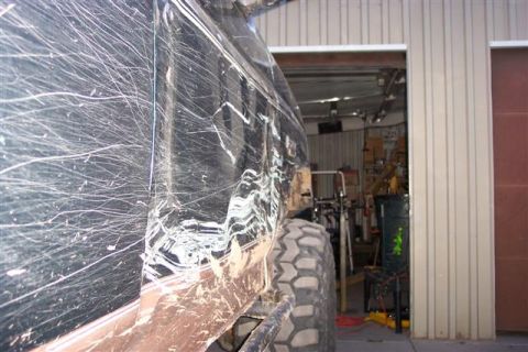 1994 Ford Bronco - Side view of a heavily scratched black SUV with mud splatter and a large off-road tire.
