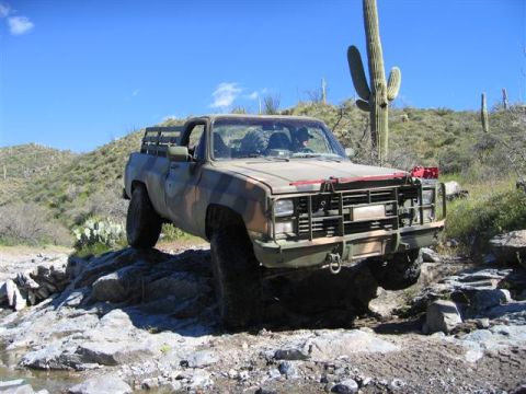 1994 Ford Bronco - This pickup truck navigates a rocky desert terrain under a clear blue sky.