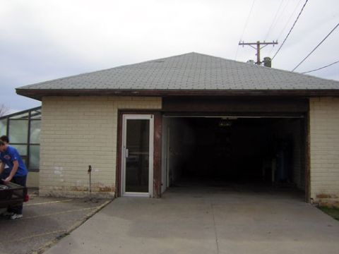 1995 Ford Bronco - A garage with a large open door and a person loading items into a trailer parked in front.