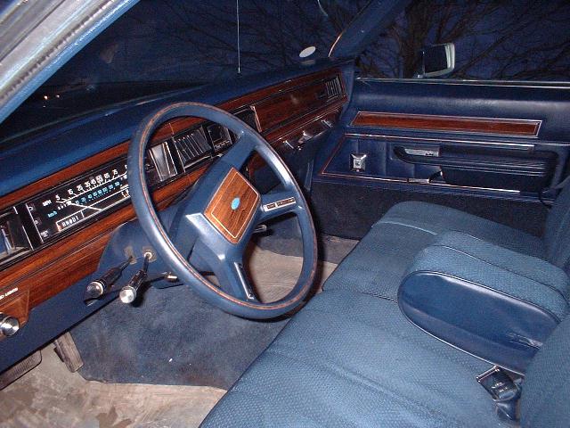 Blue interior of an older car with woodgrain dash and bench seat