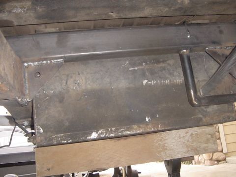 1971 Ford Bronco - A close-up view of a vehicle's undercarriage frame, showing some stamped markings and a section of black tubing.
