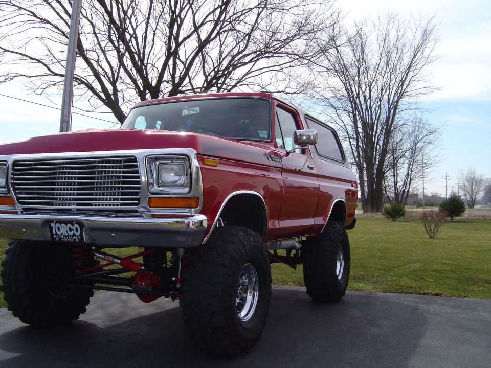 Red 1978 Ford Bronco lifted with aftermarket wheels and tires, parked outdoors