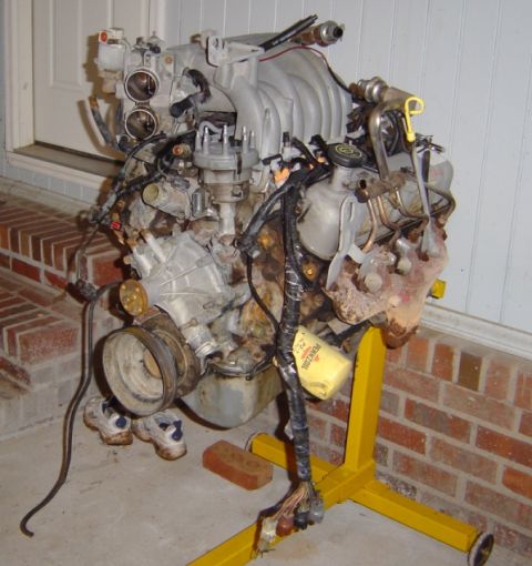 1986 Ford Bronco - Engine assembly, likely a Ford 302 or 351 Windsor, mounted on a yellow engine stand.