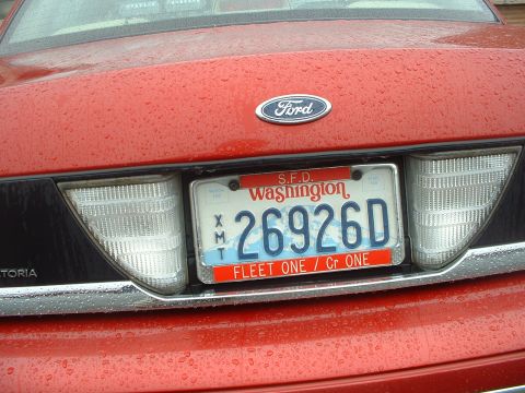 1999 Ford Crown Victoria - The back of a red Ford sedan is shown, with a license plate from Washington state.