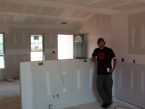 1986 Ford Bronco - A man stands in an unfinished room with drywall and exposed ceiling joists.
