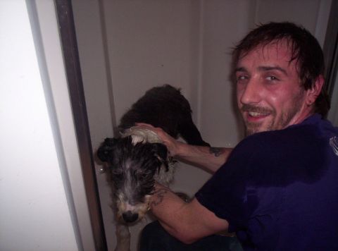 1986 Ford Bronco - A man washes a dog in a shower stall, with water droplets visible on the dog and the man's shirt.