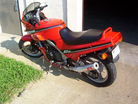 1986 Ford Bronco - A red Kawasaki EX motorcycle is parked outdoors next to a building.