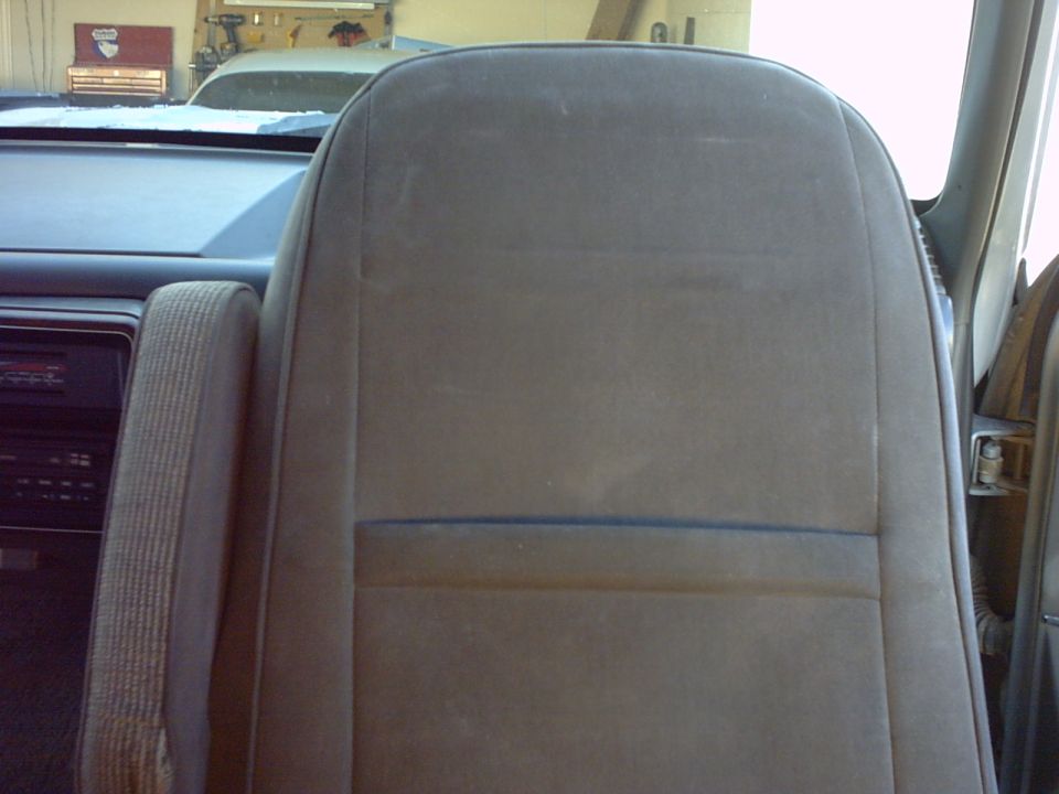 Interior shot of a vehicle's passenger seat and dashboard. A toolbox is visible in the background
