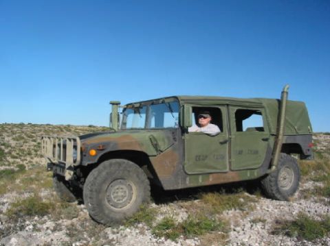 1996 Ford Bronco - A camouflage Humvee sits in a dry, rocky area with a driver behind the wheel.
