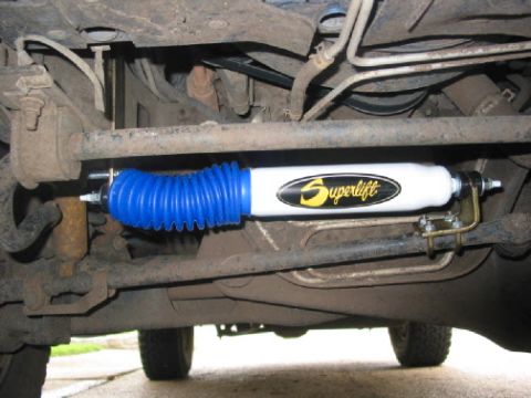 1996 Ford Bronco - Underside view of a Superlift steering stabilizer with a blue protective boot.