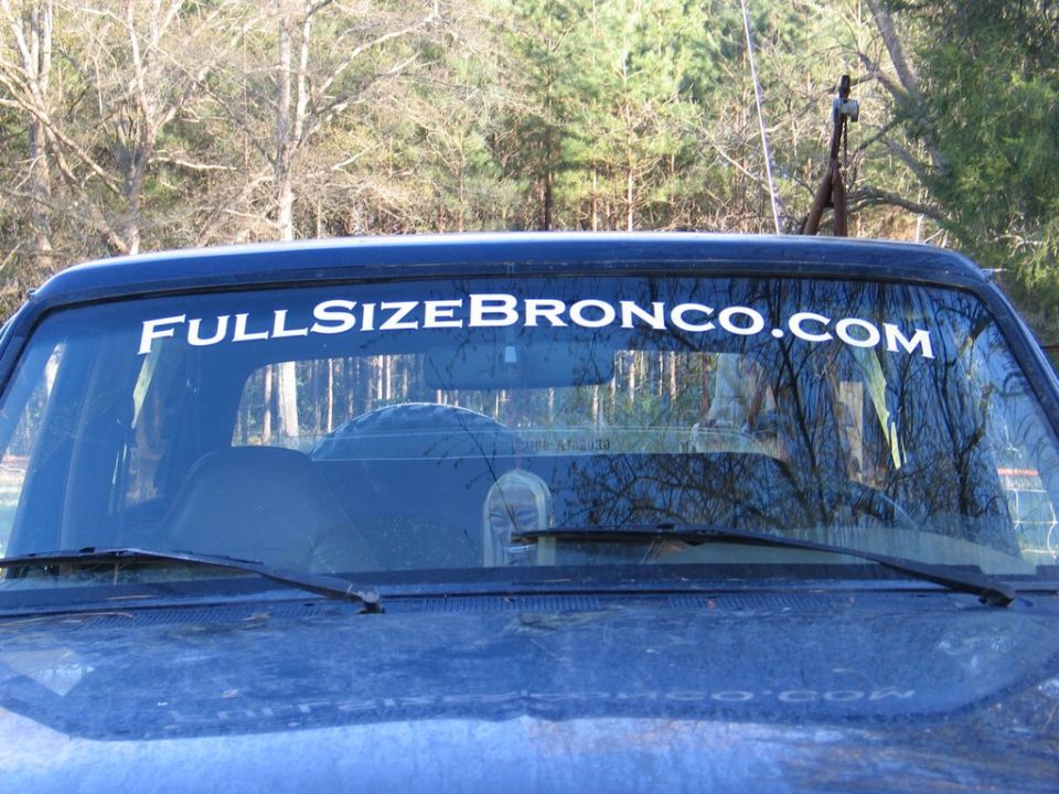 View of a dark blue Ford Bronco's windshield with a white sticker that says "FULLSIZEBRONCO.COM"