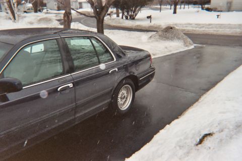 2000 Ford Crown Victoria - Side view of a dark 2000 Ford Crown Victoria parked on a wet driveway during winter.