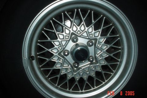 2000 Ford Crown Victoria - Close-up of a wire wheel, showing the intricate spoke design and a Ford logo on the center cap.