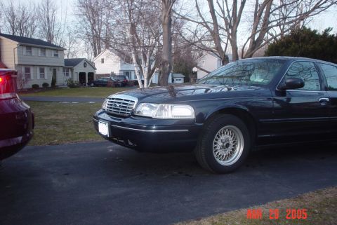 2000 Ford Crown Victoria - A dark blue 2000 Ford Crown Victoria is parked on a driveway in front of a suburban house.