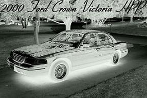 2000 Ford Crown Victoria - A black-and-white photo of a four-door sedan shown in a 3/4 front view, with a glowing underbody light effect and the caption '2000 Ford Cr…