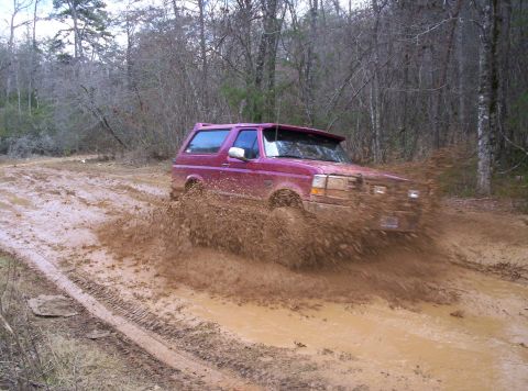 1995 Ford Bronco - Ford Bronco navigating a deep mud puddle on an off-road trail.