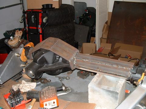 1995 Ford Bronco - A heavily modified differential housing is shown in a workshop setting with tools and tires in the background.
