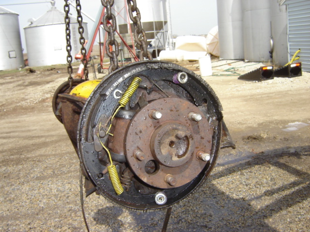 Brake drum assembly with yellow springs and rusty hub, suspended by chains