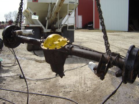 1992 Ford Bronco - A rear axle assembly is shown suspended by chains, with a large white truck in the background.
