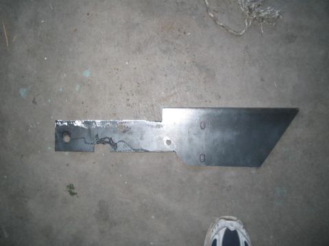 1991 Ford Bronco - A custom metal bracket lies on a concrete floor, showing signs of fabrication and modification.