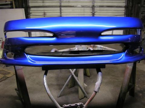 1994 Ford Probe - A freshly painted blue bumper is shown on sawhorses in a garage.