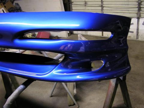 1994 Ford Probe - A freshly painted blue car bumper is shown on sawhorses in a garage.