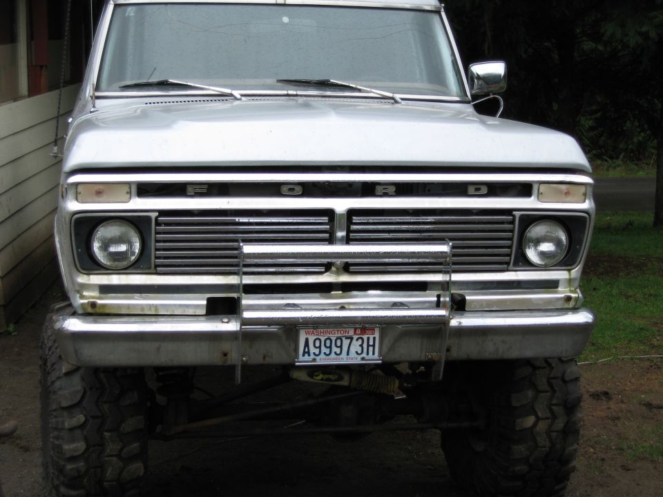 Front view of lifted silver Ford pickup with chrome grille guard, big tires, and Washington plate A99973H