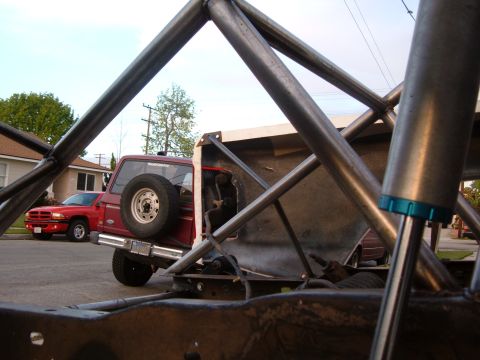 2002 Ford Ranger - A red pickup truck is parked on a street, viewed through a metal roll cage structure.