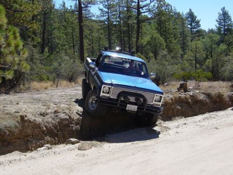 1979 Chevrolet C/K Pickup - Blue 1979 Chevrolet C/K Pickup navigates an off-road trail, with one tire in a ditch.