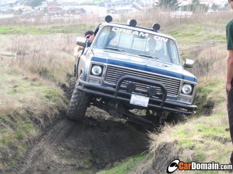 1979 Chevrolet C/K Pickup - A blue pickup truck navigates a muddy off-road trail with a "DREAM ON" decal on its windshield.