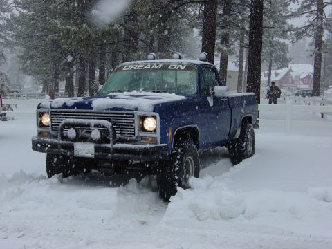 1979 Chevrolet C/K Pickup - 1979 Chevrolet C/K Pickup navigating a snowy landscape with 'DREAM ON' visible on the windshield.
